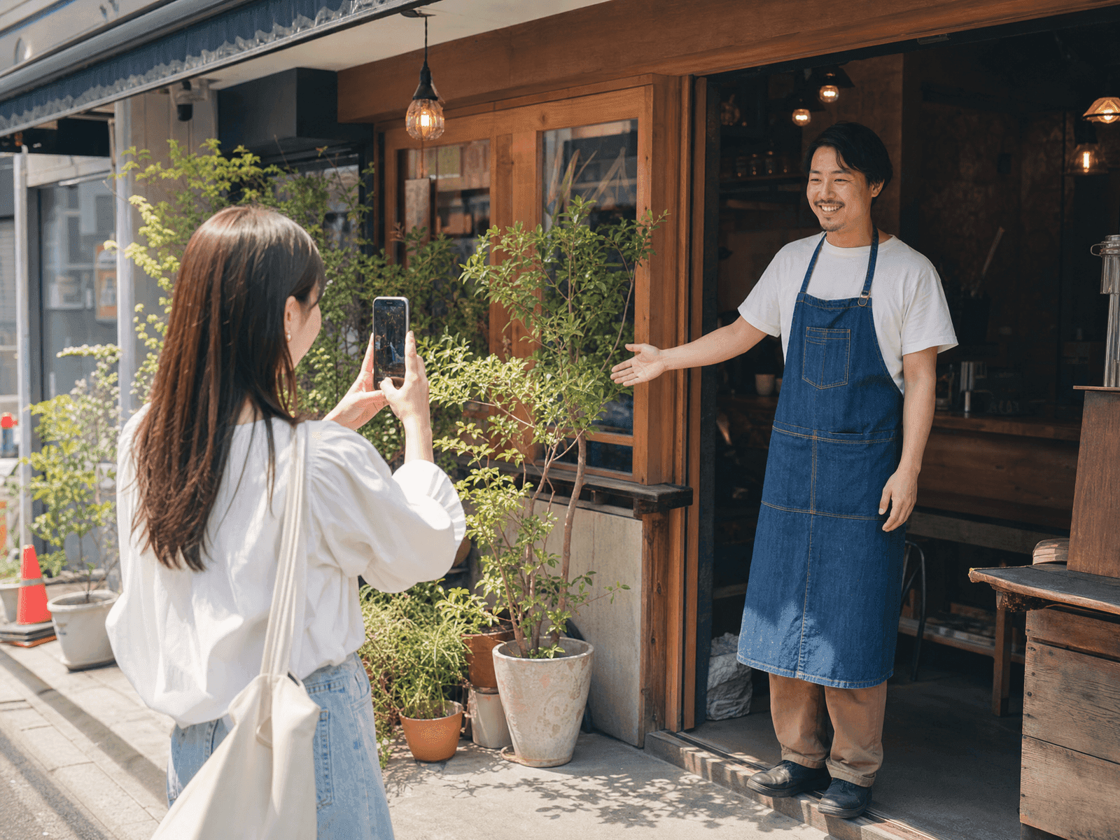 店舗前でスマホ撮影するインフルエンサーと出迎える店主